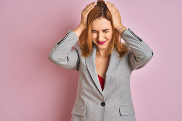 Young caucasian business woman wearing a suit over isolated pink background suffering from headache desperate and stressed because pain and migraine. Hands on head.