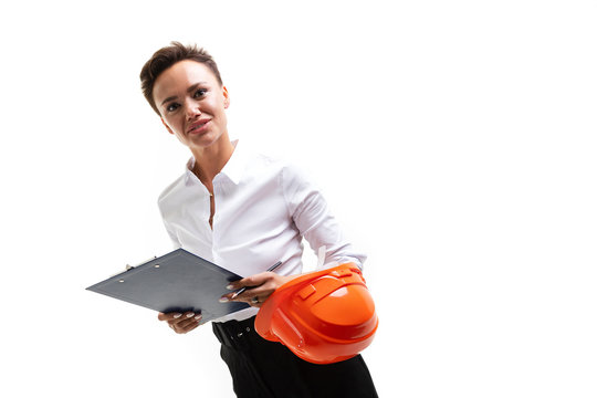Cheerful lady with short dark hair, in beautiful office suit, orange comstruction helmet plans something with tablet isolated on white background