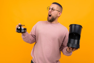 A young strong man holds a coffee maker