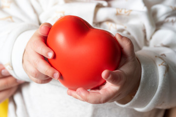 a small child holds a red heart in his hands. Concept of maternal love, child health