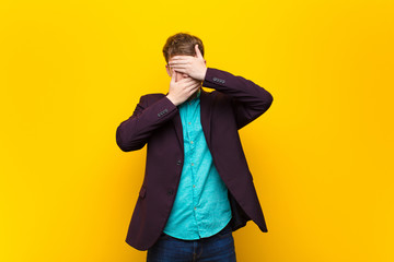 young blonde man covering face with both hands saying no to the camera! refusing pictures or...