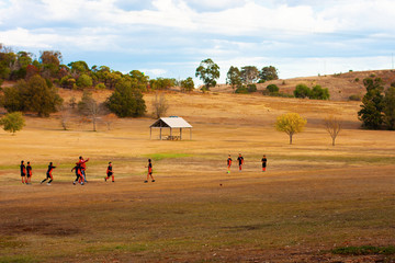Obraz premium A group of children in the distance playing football (soccer) in a clearing (a meadow) among the hills