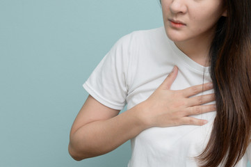 Asian woman haveing The symptoms of acid reflux. Burning sensation in the chest. Her expression indicates pain.