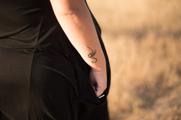 Primer plano de un tatuaje en plena naturaleza con puesta de sol. Mujer curvy.