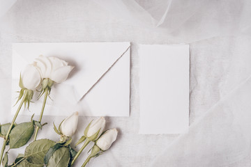 Wedding mockup. Flowers composition. White paper, roses on white textile background. Valentine's Day. Flat lay, top view, copy space