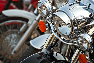 Motorcycles are placed in a row. Headlight closeup. Motorcycle chrome elements.