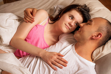 a man and a woman lie in an embrace in a bed