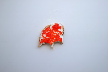Bitten sandwich with curd cheese and red caviar on a white background