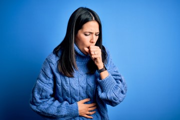 Young brunette woman with blue eyes wearing casual turtleneck sweater feeling unwell and coughing as symptom for cold or bronchitis. Health care concept.