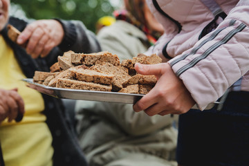 Woman handing out slices of brown bread to old people