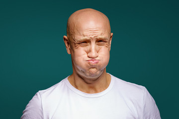 portrait of a bald man puffed out his cheeks on a blue background