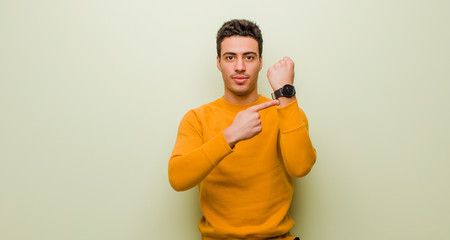 young arabian man looking impatient and angry, pointing at watch, asking for punctuality, wants to...