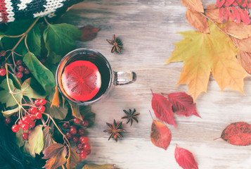 Cozy warm  still life of autumn dry leaves, red tea with lemon and red berries of viburnum