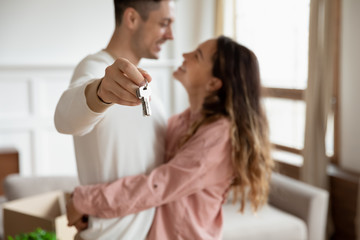 Happy young couple show house keys moving together