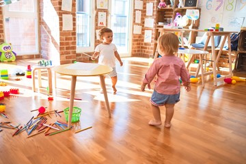 Adorable toddlers playing around lots of toys at kindergarten