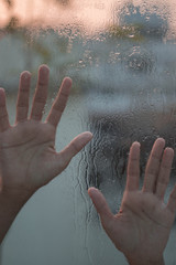 Human hands on a raindrop window 