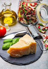 Cheese collection, piece of hard aged Italian parmesan or grana padano cheese with olive oil and tricolore italian pasta