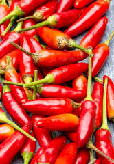 Fresh small red hot chili peppers on grey background