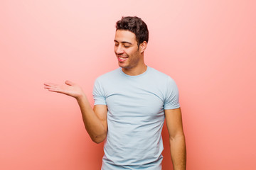 young arabian man feeling happy and smiling casually, looking to an object or concept held on the...