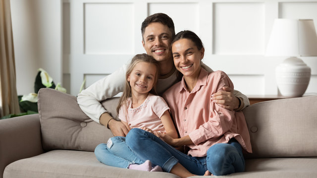 Portrait of happy young family with daughter relaxing on couch