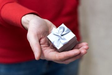 Closeup on hands man giving a small gray gift box