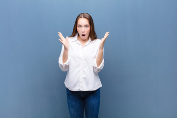 young blonde pretty girl looking shocked and astonished, with jaw dropped in surprise when...