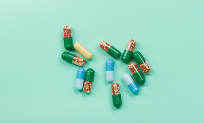 Green and blue medicinal capsules on a green background
