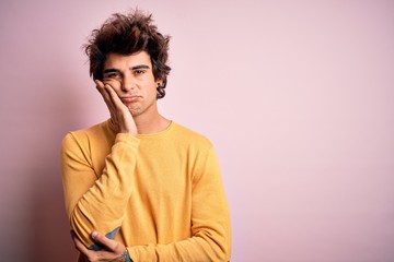 Fototapeta na wymiar Young handsome man wearing yellow casual t-shirt standing over isolated pink background thinking looking tired and bored with depression problems with crossed arms.