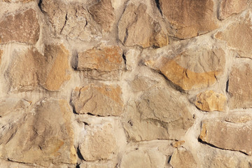 Ancient medieval stone masonry. Texture of a fragment of a wall of an old structure. A background for design and creative work. Decoration and exterior decoration of the building. Construction works