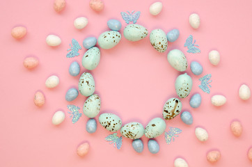 Easter circle shape frame made of decorated quail eggs on a pink table. Top view with space for lettering