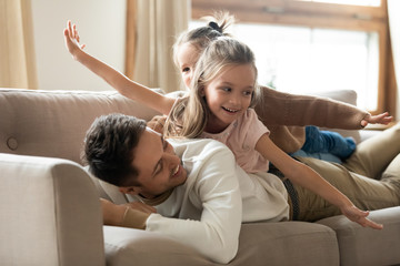 Loving young dad playing with little daughters at home