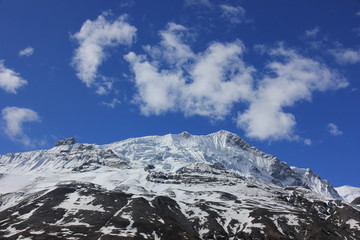 Fototapeta na wymiar Snowy mountains against the blue sky with white clouds. Mountains of Nepal