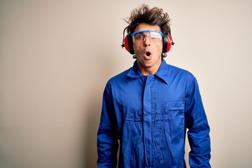 Young constructor man wearing uniform and earmuffs over isolated white background afraid and shocked with surprise expression, fear and excited face.