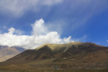 Obraz premium Brown mountains against the blue sky with white clouds