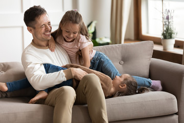 Obraz premium Overjoyed young dad playing with daughters in living room