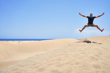 Young handsome man jumping at the beach