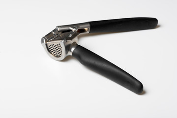 Metallic garlic press on white table