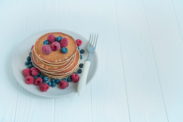 Pancakes with fresh berries on a light background. Pancakes with fruits. Traditional american breakfast. Homemade dish. Copy space. The balance of healthy eating.
