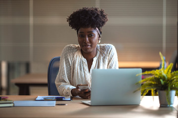 Shot of a young businesswoman using a laptop at work. Portrait of young black woman in creative...