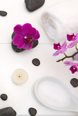 Spa setting with pink orchids, black stones on white wood background.