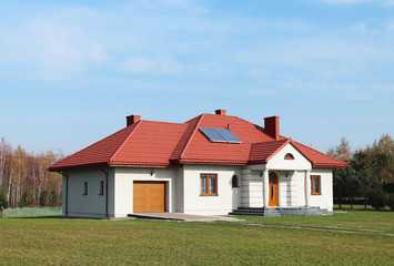 Fototapeta na wymiar Jaslo, Poland - 7 8 2018: Modern design of a small single-family house located in a rural area. Designing buildings and landscape. New home for people. Red metal roof. Energy saving and greenhouse eff