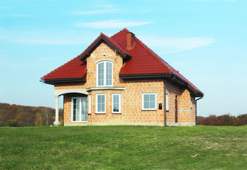 Fototapeta na wymiar Jaslo, Poland - 7 8 2018: Modern design of a small single-family house located in a rural area. Designing buildings and landscape. New home for people. Red metal roof. Energy saving and greenhouse eff