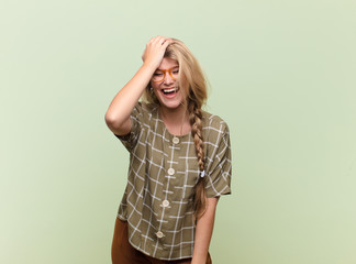 young pretty latin woman laughing and slapping forehead like saying d‚Äôoh! I forgot or that...