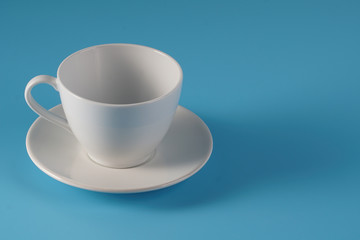 White ceramic cup over isolated blue bcakground