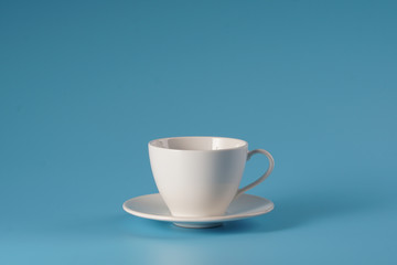 White ceramic cup over isolated blue bcakground