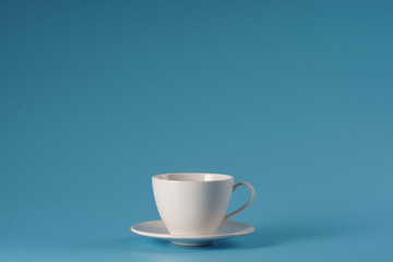 White ceramic cup over isolated blue bcakground