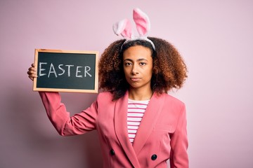 African american woman with afro hair wearing bunny ears holding blackboard with message with a...