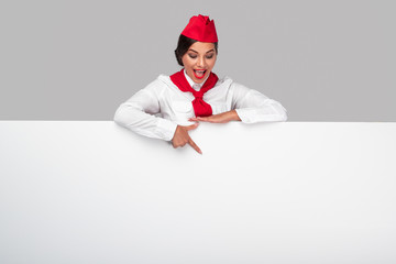 Excited stewardess pointing at empty poster