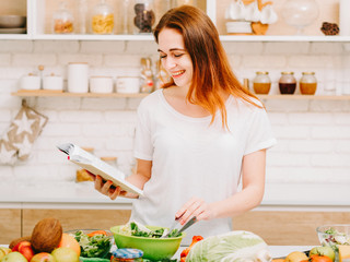 Cooking hobby. Fun home leisure. Woman reading recipe to prepare meal in kitchen.