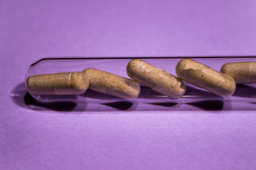 Pills, antibiotics, natural preparations half in a glass test tube on a purple background d